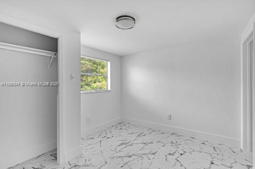 A bright, empty bedroom features white walls, a closet, and white marble-patterned tile flooring — 54 NW 62nd St # 4, Miami FL 33150, MIAMI, FL