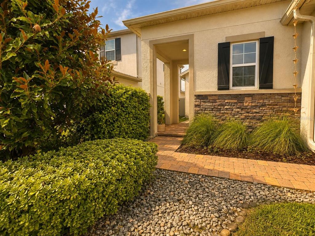 A paved walkway leads to the recessed entryway of a house with stone veneer siding — 1463 SOURWOOD DRIVE, OCOEE, FL