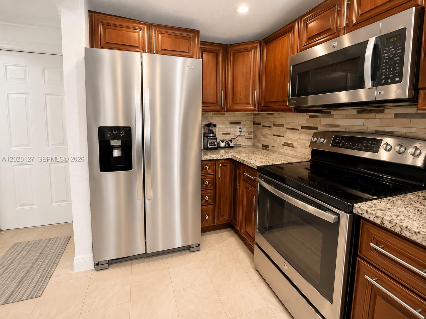 A kitchen features stainless steel appliances, dark wood cabinetry, and granite countertops — 1901 NW S River Dr # 5A, Miami FL 33125, MIAMI, FL