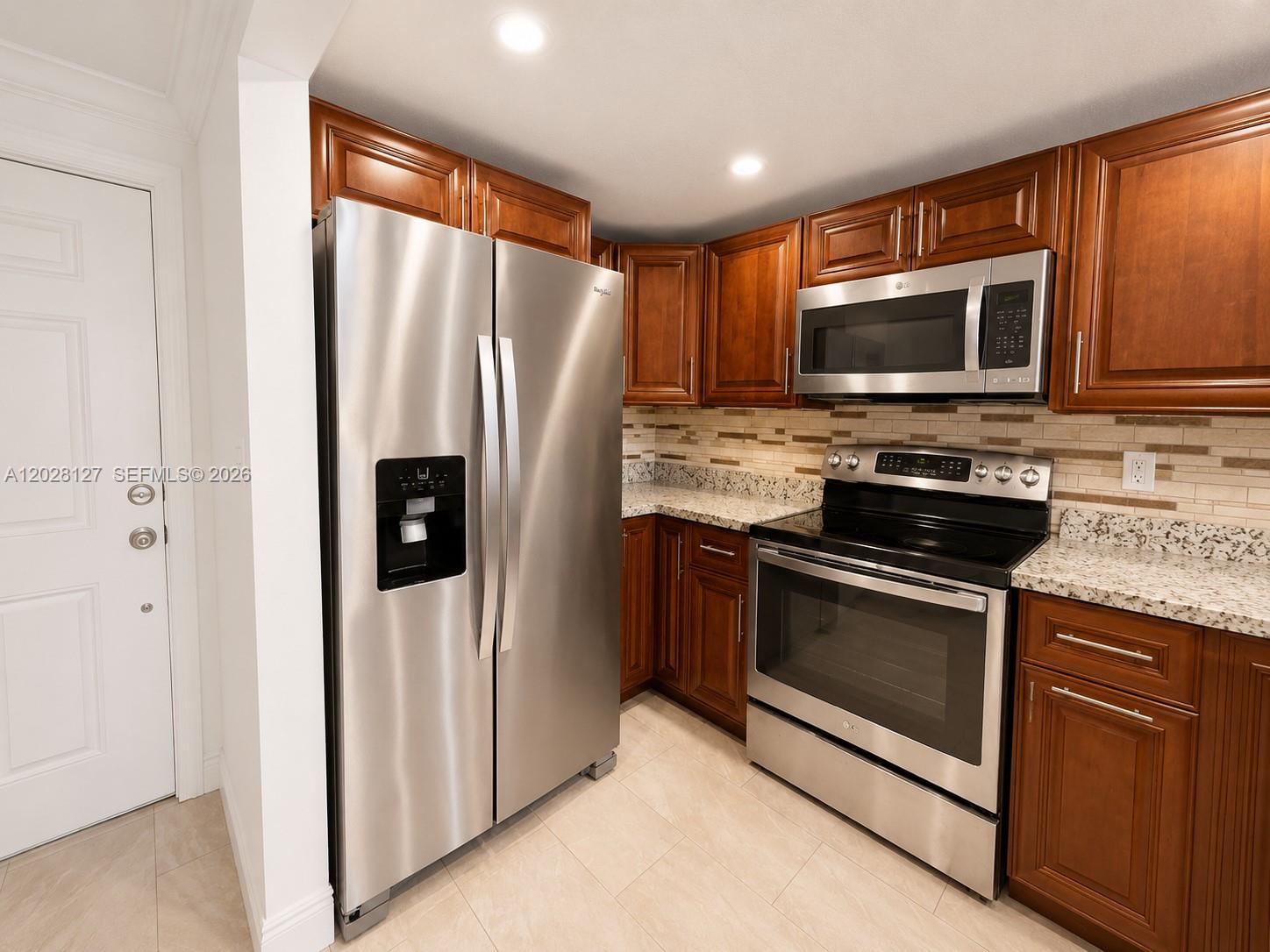 A kitchen features stainless steel appliances, dark wood cabinets, and granite countertops — 1901 NW S River Dr # 5A, Miami FL 33125, MIAMI, FL