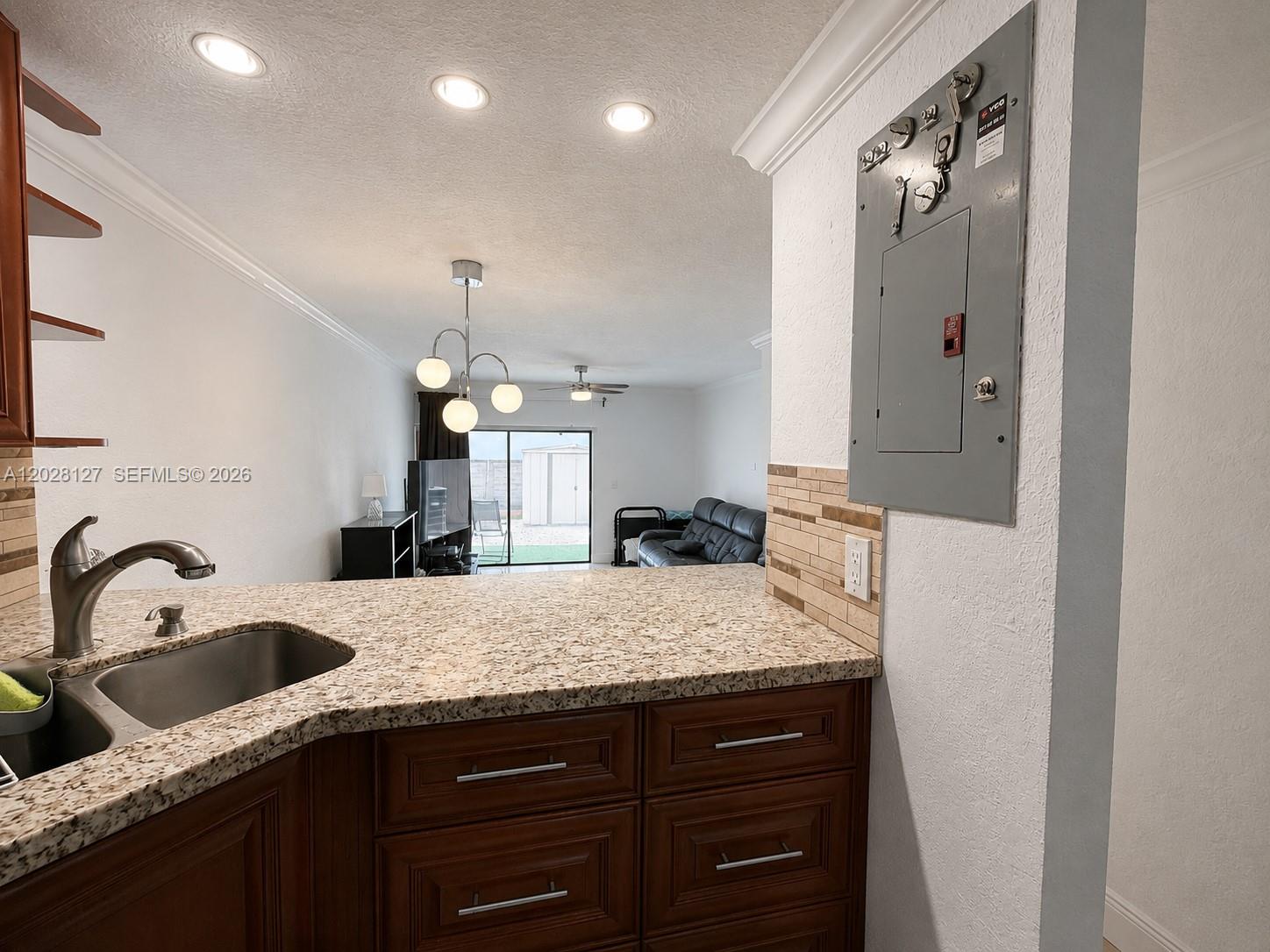 A kitchen counter with a sink overlooks a living area with a sliding glass door — 1901 NW S River Dr # 5A, Miami FL 33125, MIAMI, FL