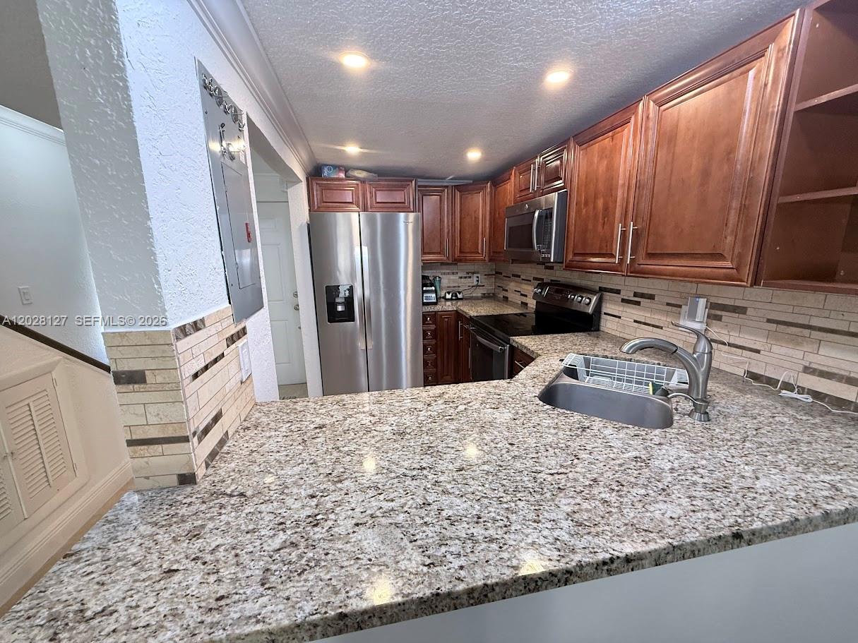 A kitchen features granite countertops, wood cabinets, stainless steel appliances, and a tiled backsplash — 1901 NW S River Dr # 5A, Miami FL 33125, MIAMI, FL