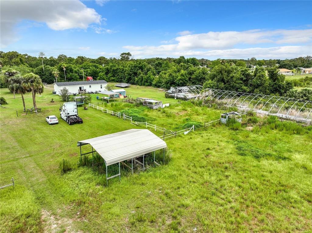 An aerial view of a rural property featuring a house, outbuildings, and a large greenhouse frame — 3345 RAMBLER AVENUE, ST CLOUD, FL