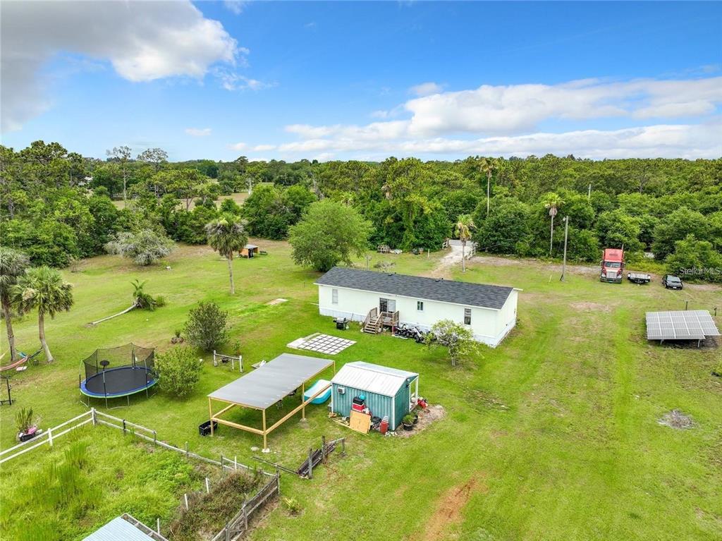An aerial view shows a mobile home on a large, grassy lot with outbuildings — 3345 RAMBLER AVENUE, ST CLOUD, FL