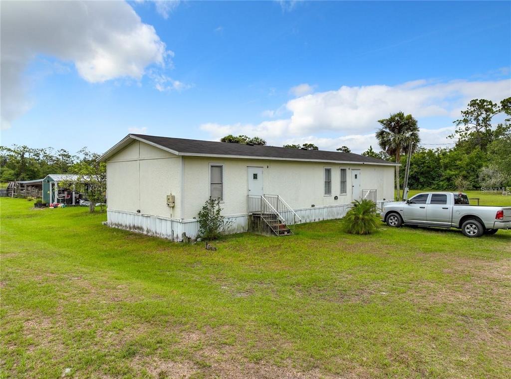 A single-story manufactured home sits on a grassy lot with a silver pickup truck parked nearby — 3345 RAMBLER AVENUE, ST CLOUD, FL