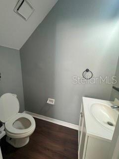 A small bathroom features a white toilet, a vanity with a sink, and dark flooring — 11253 WINDSOR PLACE CIRCLE, TAMPA, FL