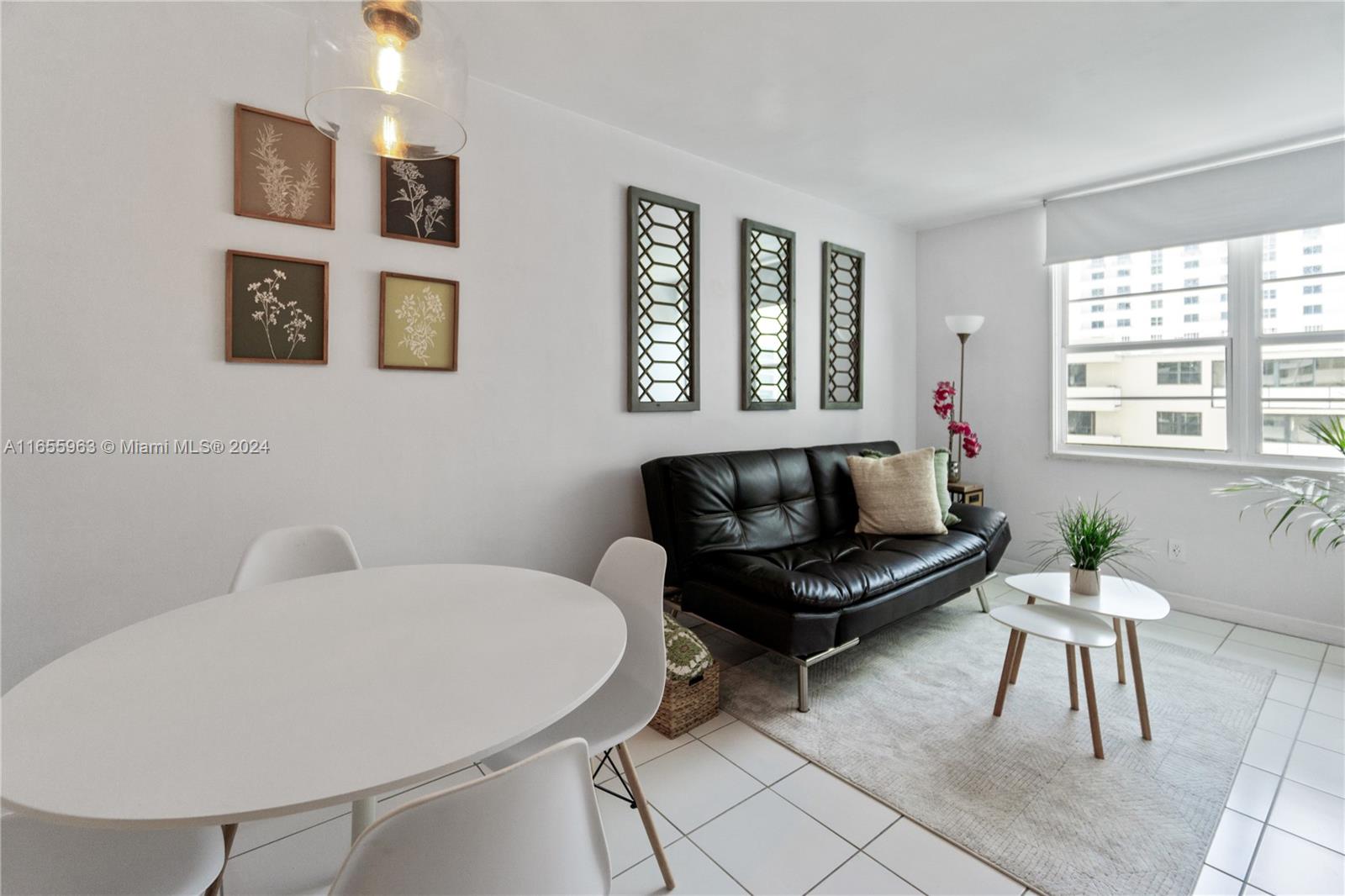A dining area and living room feature white tile floors, a black sofa, and wall art — 100 Lincoln Rd # 924, Miami Beach FL 33139, MIAMI BEACH, FL