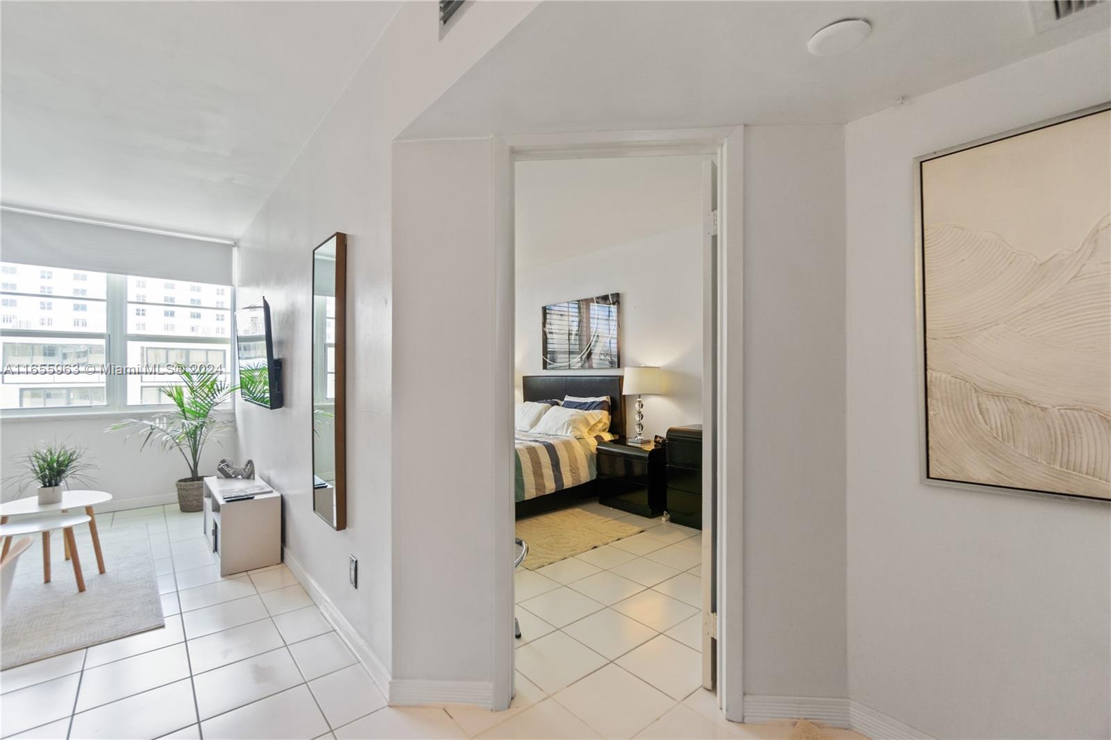 A view from a tiled hallway into a bedroom with a bed and nightstand — 100 Lincoln Rd # 924, Miami Beach FL 33139, MIAMI BEACH, FL