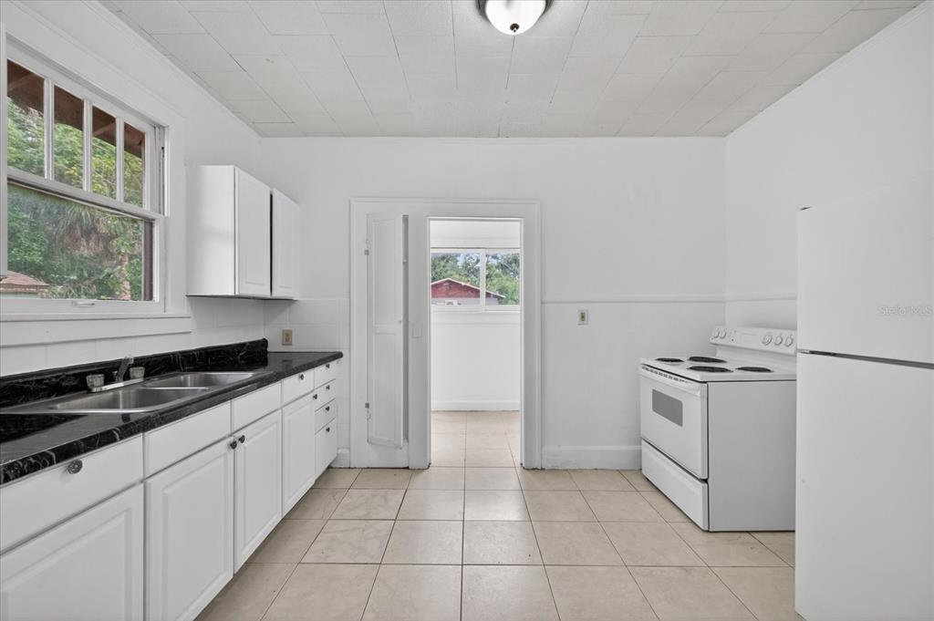 A kitchen with white cabinets, black countertops, a white stove, and a white refrigerator — 2211 22ND AVENUE S, ST PETERSBURG, FL