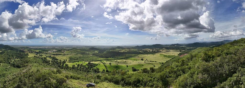 A panoramic view of a lush, hilly landscape with green fields and a distant coastline — 2565 PR545, COAMO, PR