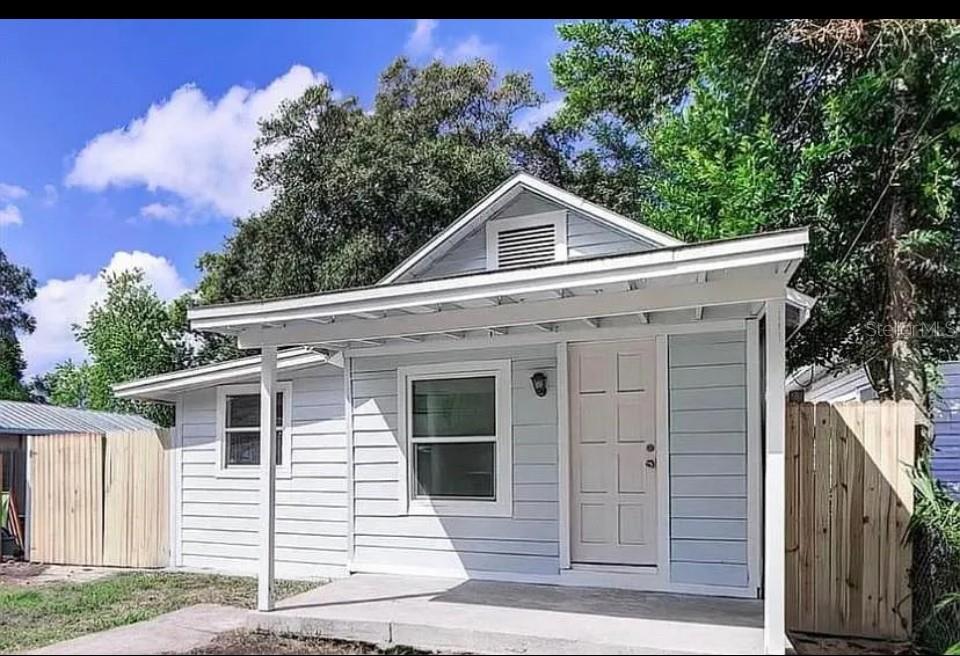 A small, light blue house with a covered front porch and a concrete entry pad — 8428 N HIGHLAND AVENUE, TAMPA, FL