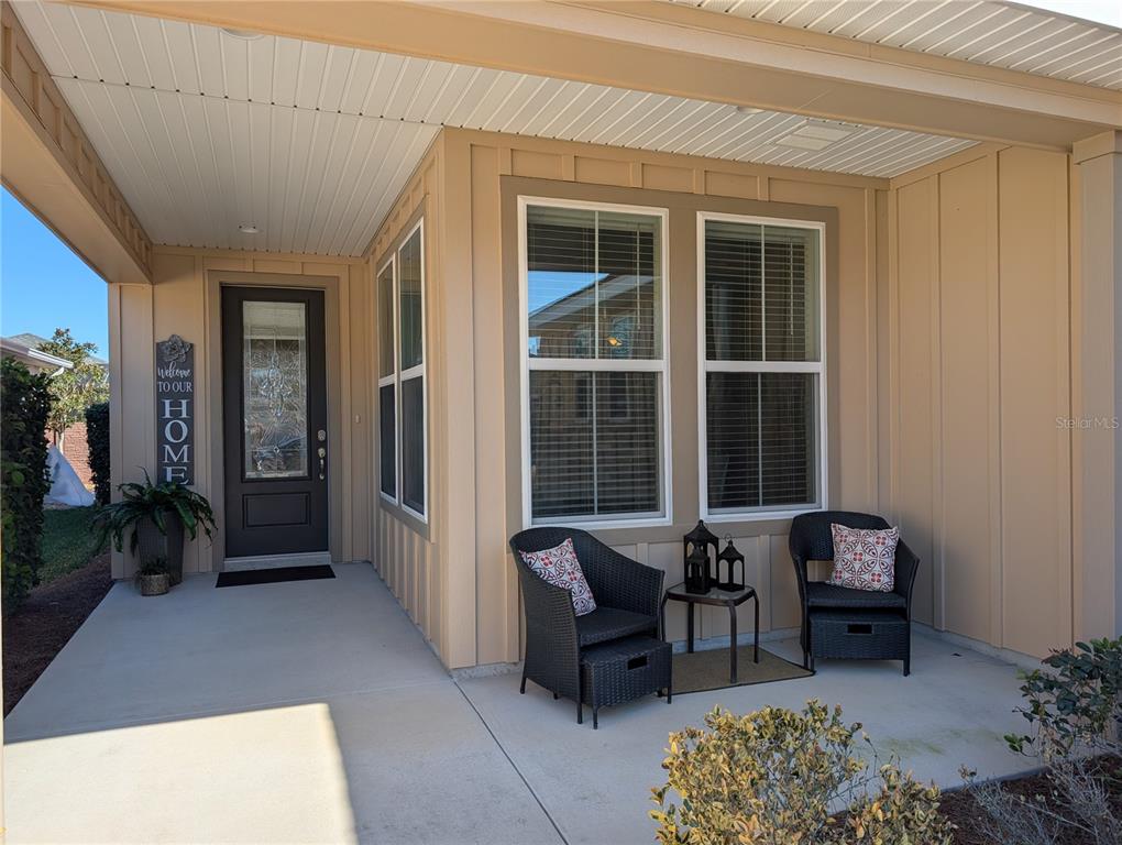 A covered front porch features a dark door, two wicker chairs, and a small table — 4341 NW 57TH AVENUE, OCALA, FL