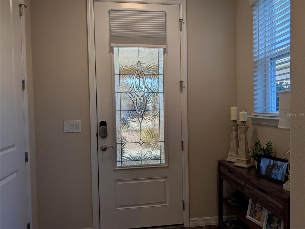 An entryway features a white front door with a decorative glass panel and a side table — 4341 NW 57TH AVENUE, OCALA, FL