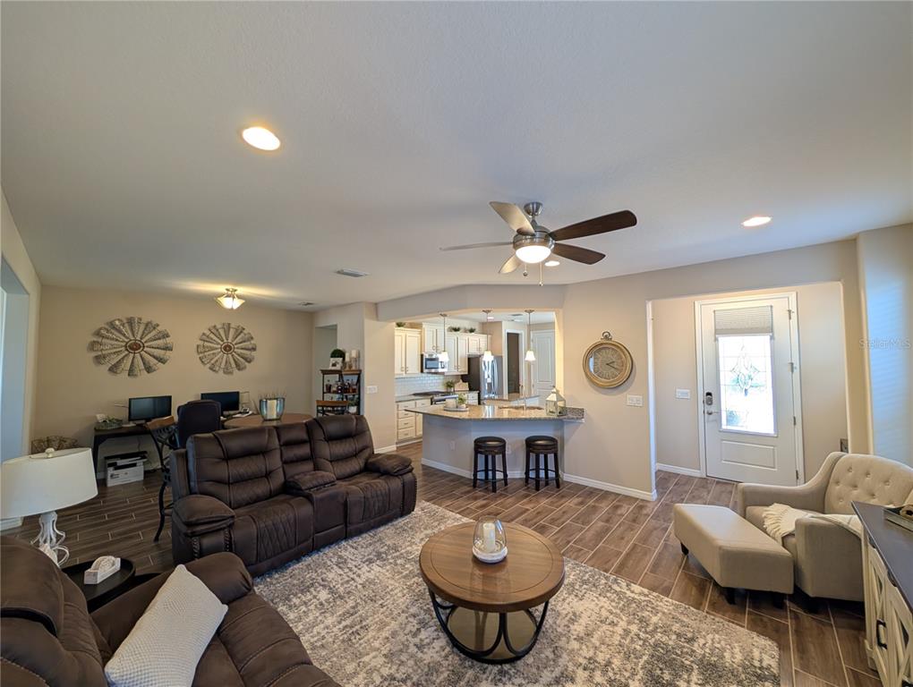 An open-concept living room features wood-look tile flooring, a kitchen island, and a ceiling fan — 4341 NW 57TH AVENUE, OCALA, FL