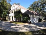 A two-story house with a columned porch and an attached garage sits on a paved driveway — 8475 NE 16TH TERRACE, OCALA, FL