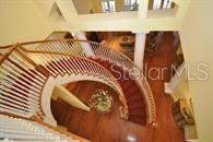 A high-angle view of a grand curved staircase with a red runner and white railings — 8475 NE 16TH TERRACE, OCALA, FL