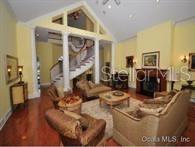 A living room features a curved staircase, tall columns, hardwood floors, and a stone fireplace — 8475 NE 16TH TERRACE, OCALA, FL