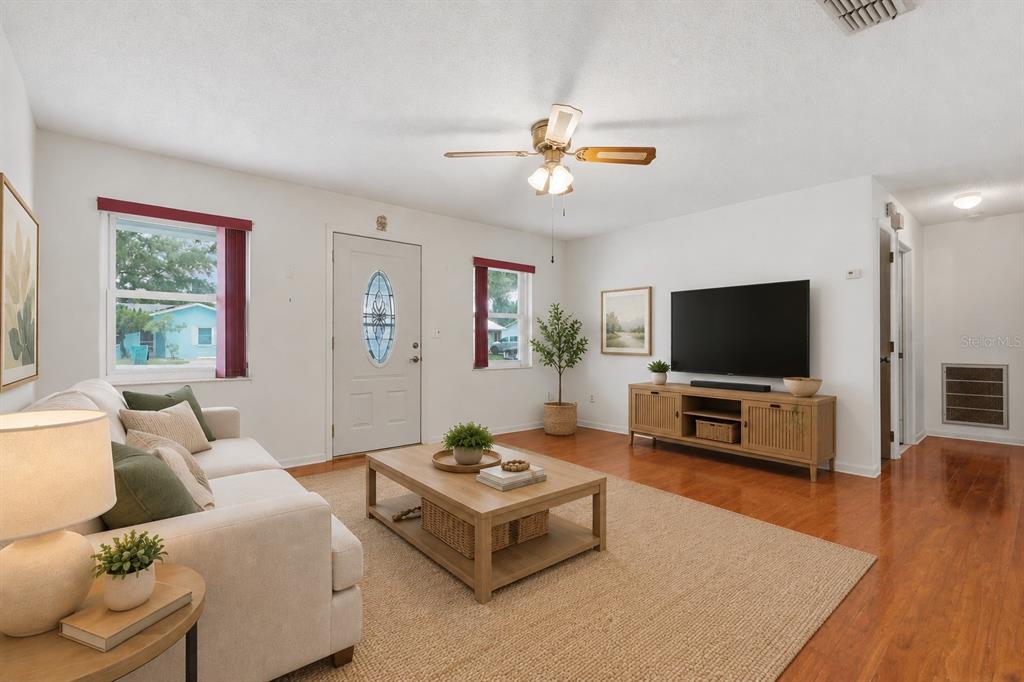 A living room features a white sofa, a wooden coffee table, and a television console — 6130 17TH STREET, ZEPHYRHILLS, FL