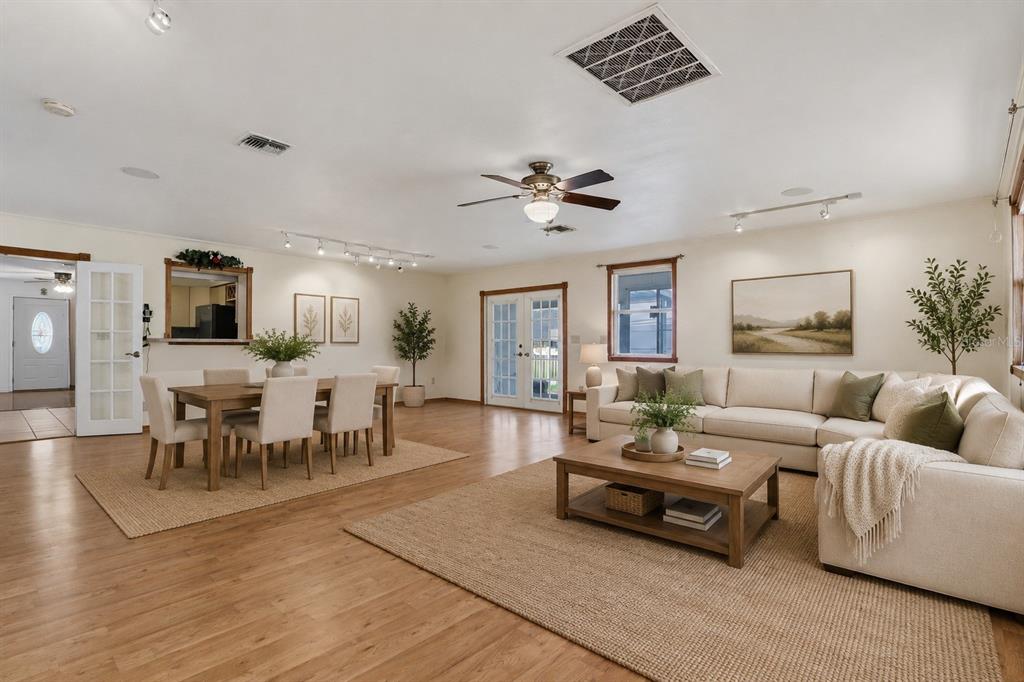 A spacious open-concept living and dining area with light wood floors and neutral furniture — 6130 17TH STREET, ZEPHYRHILLS, FL
