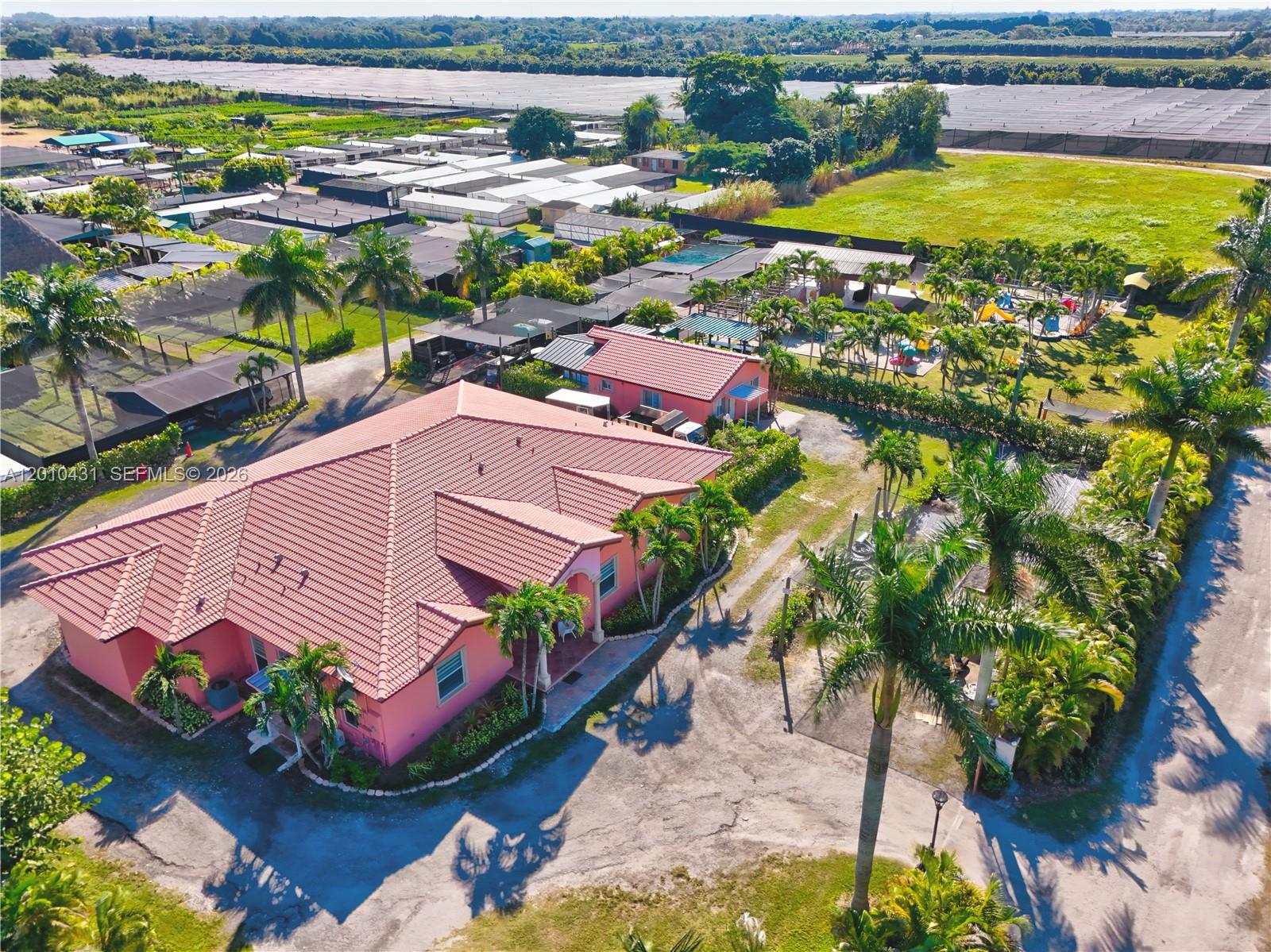 An aerial view shows a pink house with a tiled roof surrounded by palm trees — 20455 SW 154th Ave, Miami FL 33187, MIAMI, FL