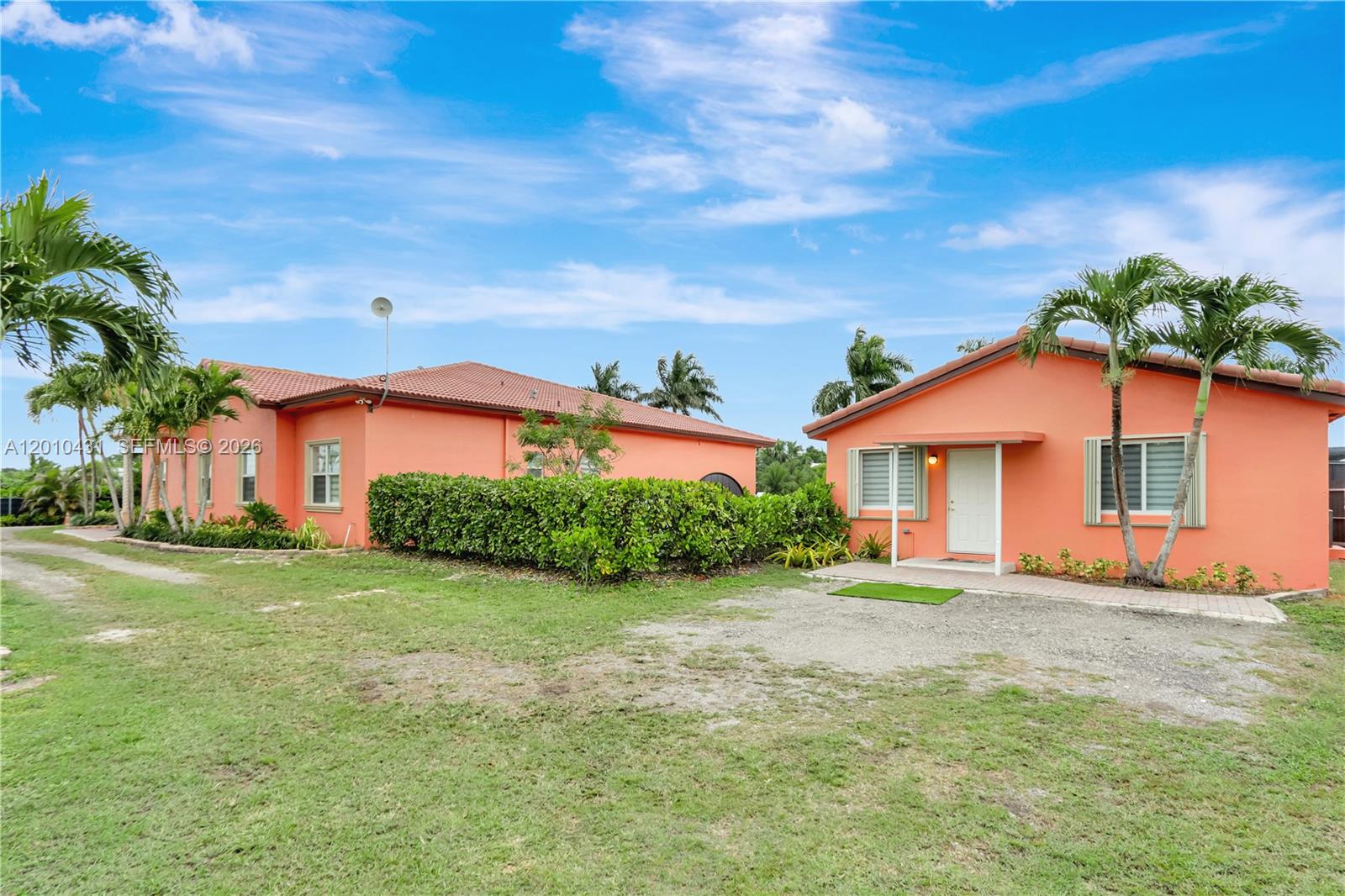 Two peach-colored houses with tiled roofs stand on a grassy lot with palm trees — 20455 SW 154th Ave, Miami FL 33187, MIAMI, FL