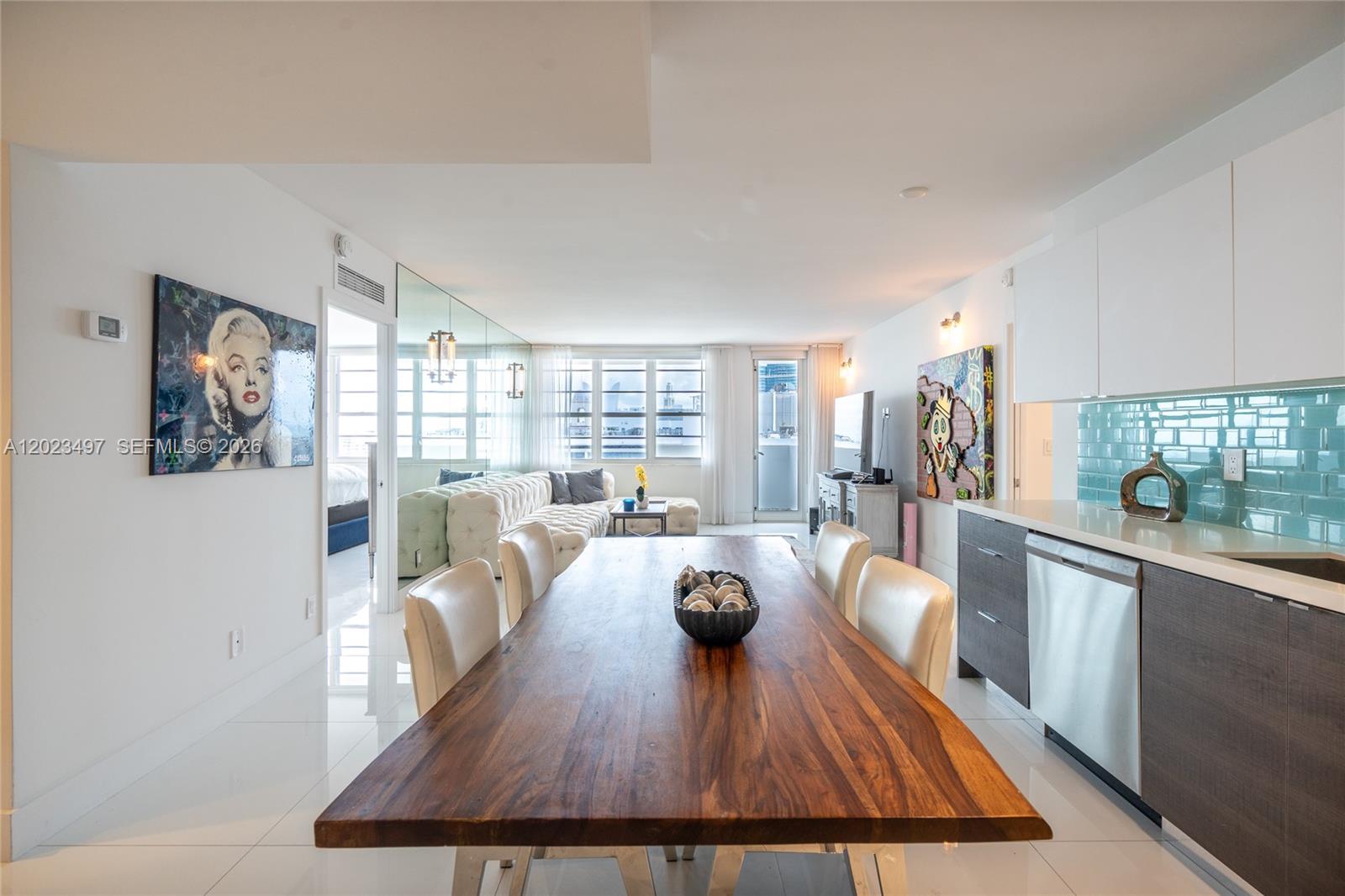 A dining area with a wooden table sits adjacent to a modern kitchen and living room — 100 Lincoln Rd # 1523, Miami Beach FL 33139, MIAMI BEACH, FL