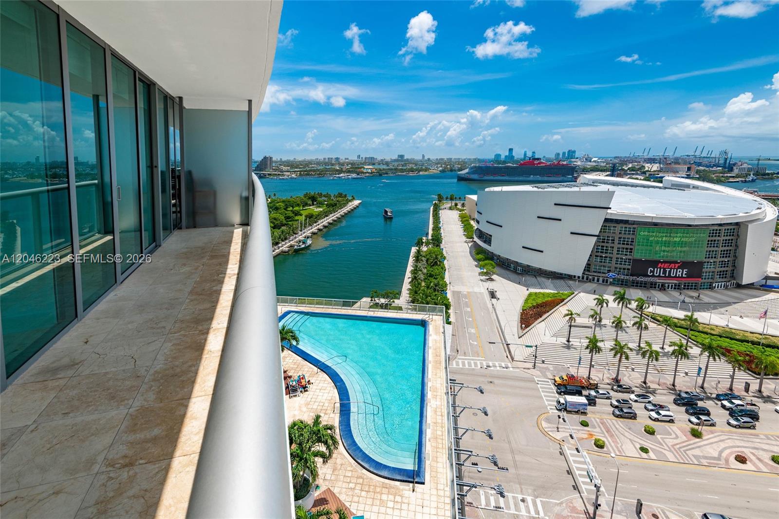 A high-rise balcony overlooks a swimming pool, a stadium, and a harbor with cruise ships — 888 Biscayne Blvd # 2002, Miami FL 33132, MIAMI, FL
