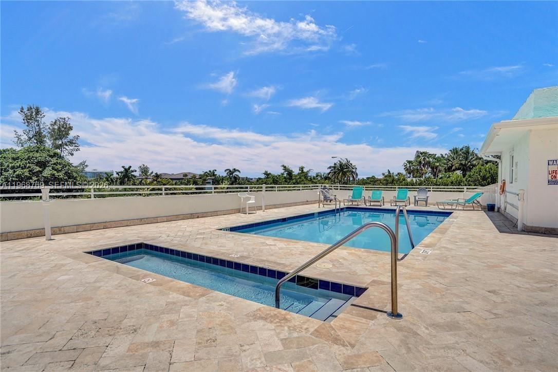 An outdoor swimming pool and hot tub on a paved deck with lounge chairs — 9156 Collins Ave # 204, Surfside FL 33154, SURFSIDE, FL