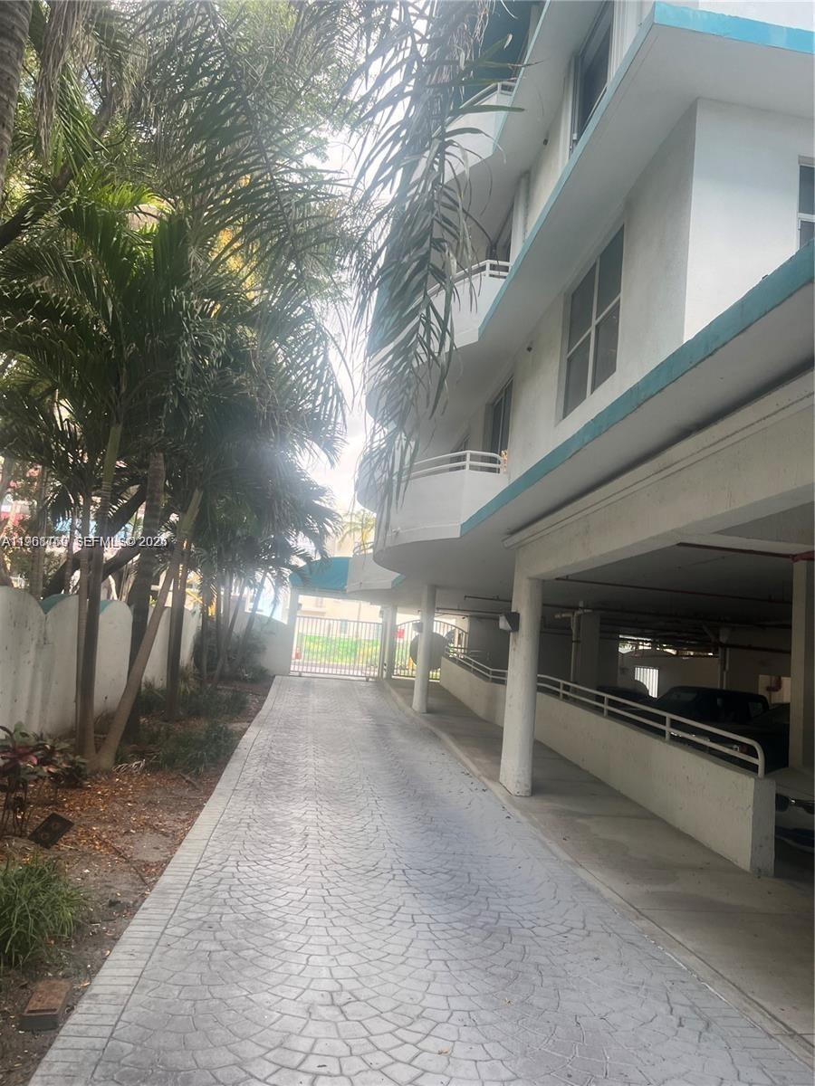 A paved driveway leads toward a gated entrance beside a multi-story building with covered parking — 9156 Collins Ave # 204, Surfside FL 33154, SURFSIDE, FL