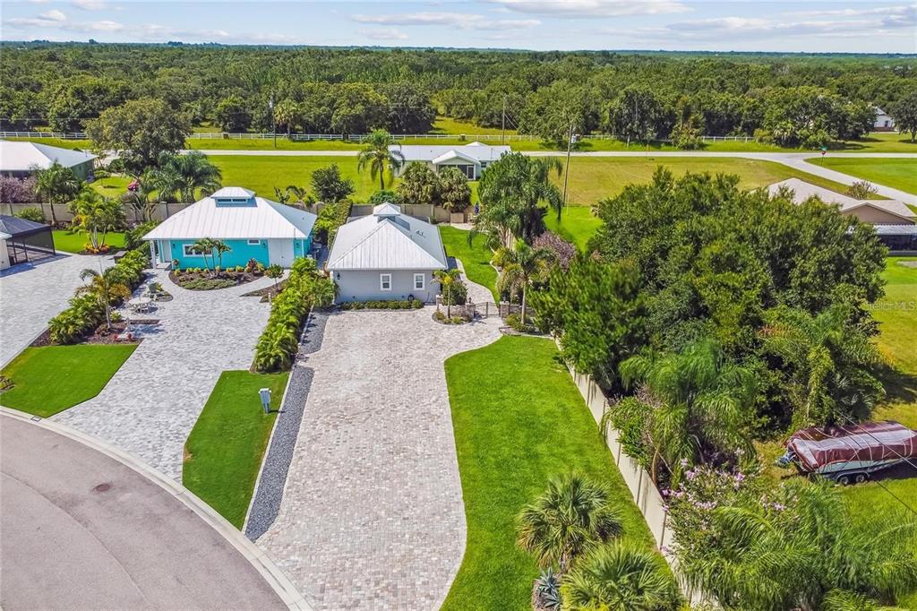 An aerial view shows two houses with metal roofs and large paver driveways in Florida — 8574 SW SAND CRANE - LOT 53 CIRCLE, ARCADIA, FL