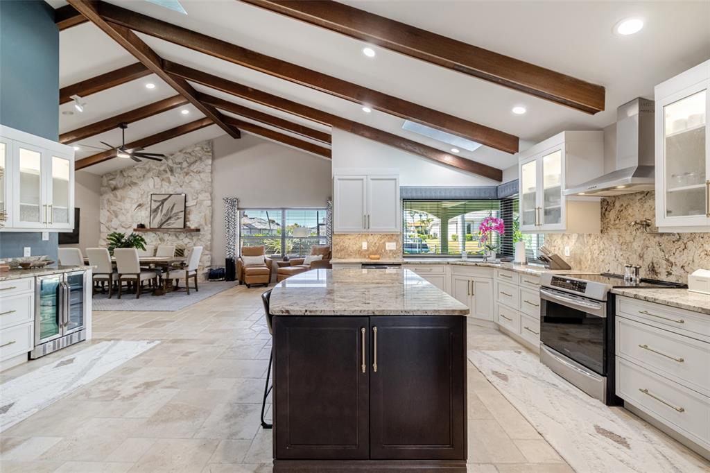 A kitchen with a dark island and white cabinets features vaulted ceilings with exposed beams — 6777 DANAH COURT, FORT MYERS, FL