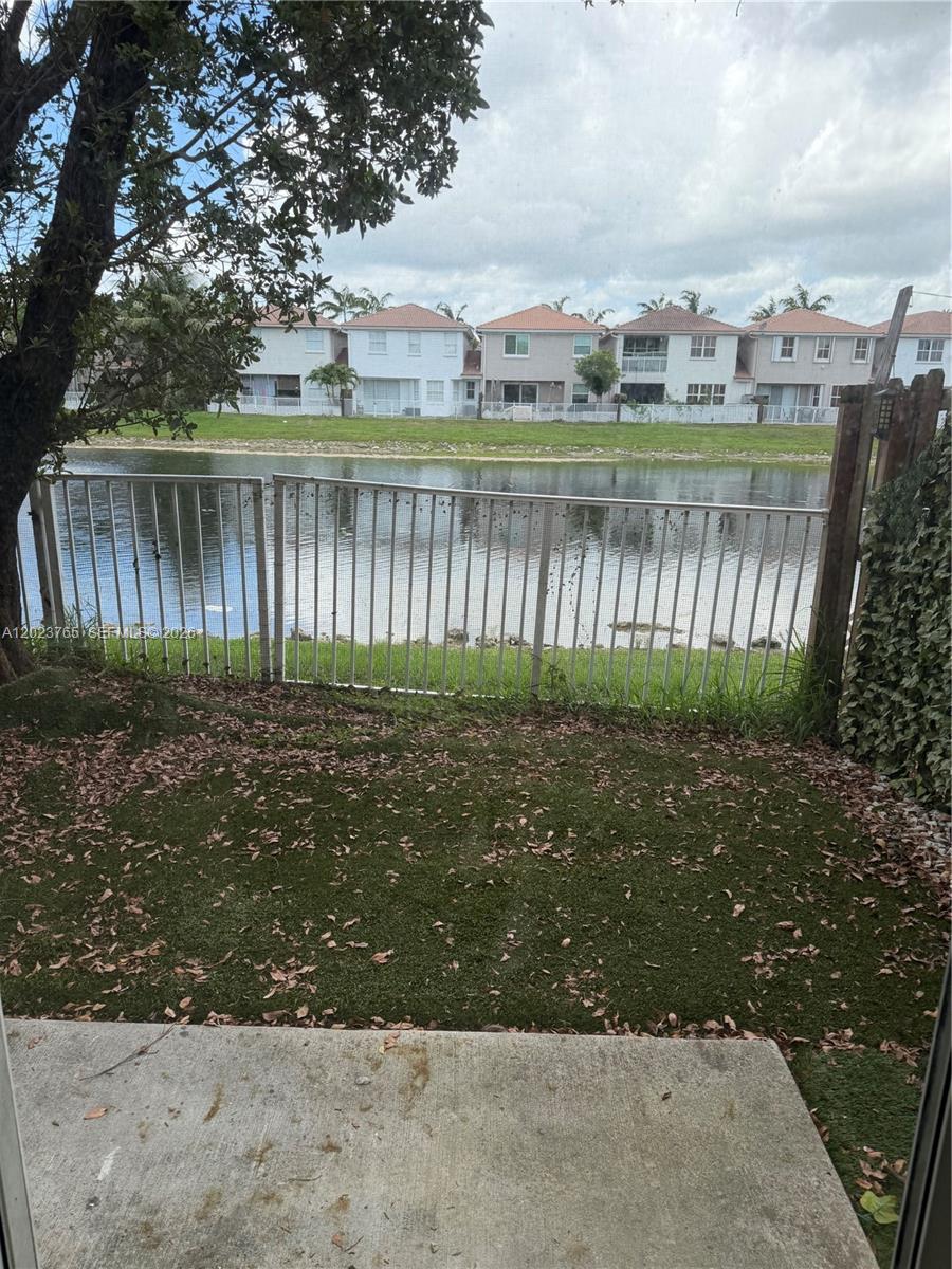 A view from a patio looking across a small grassy yard toward a lake and houses — 10803 NW 83rd St # 1, Doral FL 33178, DORAL, FL