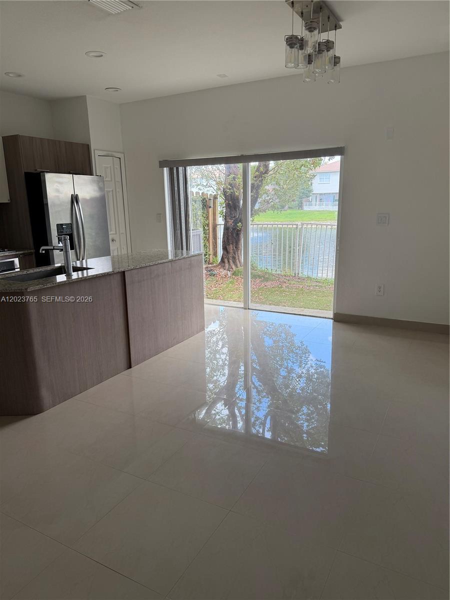 A kitchen with wood-tone cabinets and a sliding glass door overlooking a lake — 10803 NW 83rd St # 1, Doral FL 33178, DORAL, FL