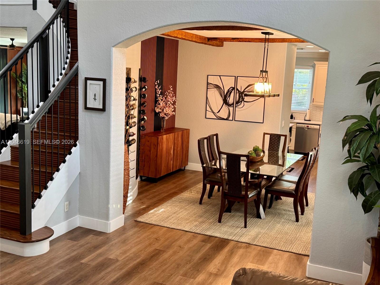 A dining room with a glass table, wooden sideboard, and wine rack under an archway — 12917 SW 23rd St, Miramar FL 33027, MIRAMAR, FL