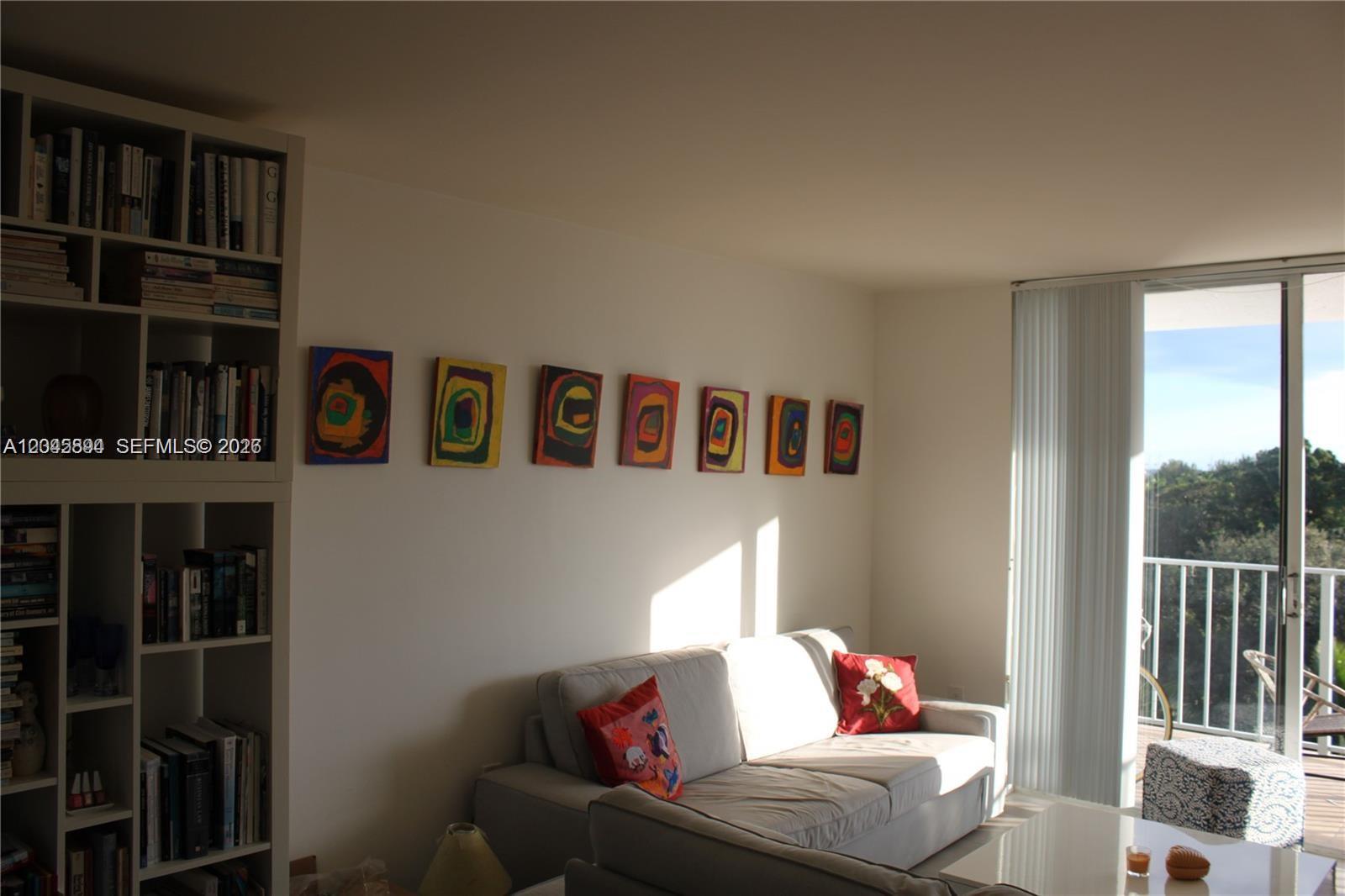 A living room features a white bookshelf, a gray sofa, and abstract art on the wall — 700 NE 63rd St, Miami FL 33138, MIAMI, FL