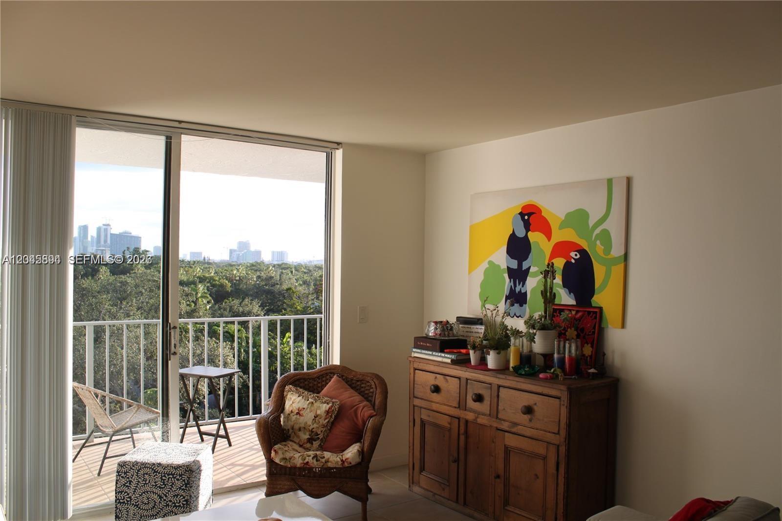 A living room features a wooden sideboard, a wicker chair, and a balcony with city views — 700 NE 63rd St, Miami FL 33138, MIAMI, FL