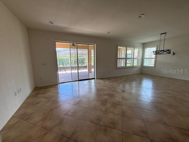 An open living area features tan tile flooring, recessed lighting, and a sliding glass door — 1284 BONITA CANYON DRIVE, POINCIANA, FL
