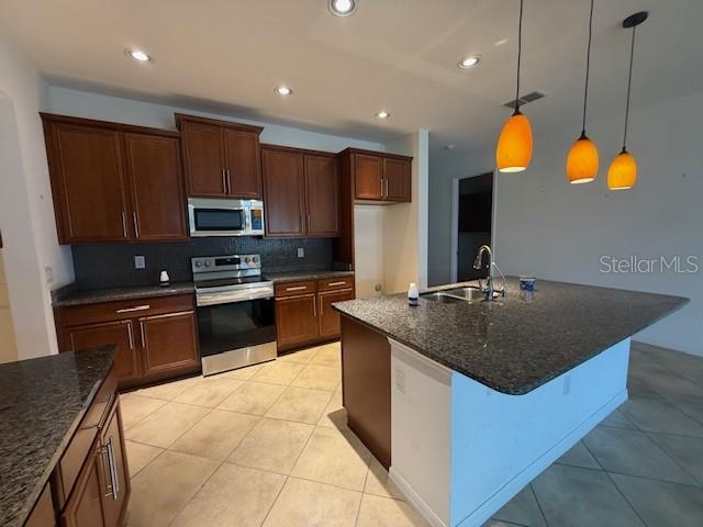 A kitchen features dark wood cabinets, granite countertops, a center island, and three pendant lights — 1284 BONITA CANYON DRIVE, POINCIANA, FL