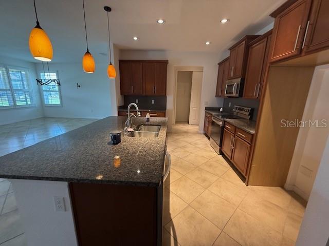 A kitchen features a granite-topped island, wooden cabinets, and tile flooring — 1284 BONITA CANYON DRIVE, POINCIANA, FL