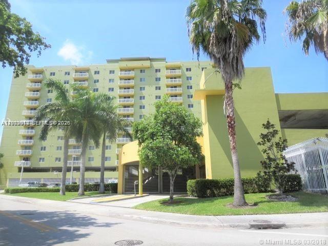 A multi-story apartment building with balconies and palm trees stands next to a parking structure — 816 NW 11th St # 801, Miami FL 33136, MIAMI, FL