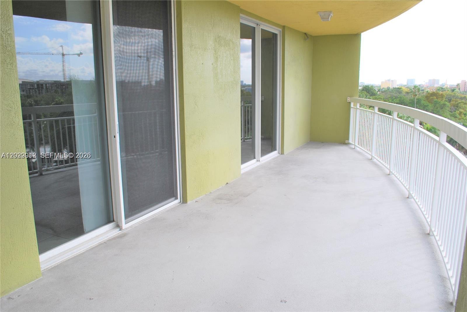 A balcony with light green walls, concrete flooring, and a white metal railing — 816 NW 11th St # 801, Miami FL 33136, MIAMI, FL