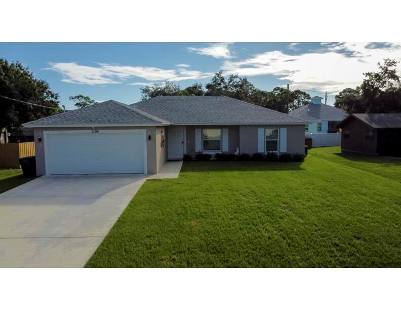 A single-story house with a gray shingled roof, beige stucco exterior, and a two-car garage — 6106 Bamboo Drive, Fort Pierce FL 34982, FORT PIERCE, FL