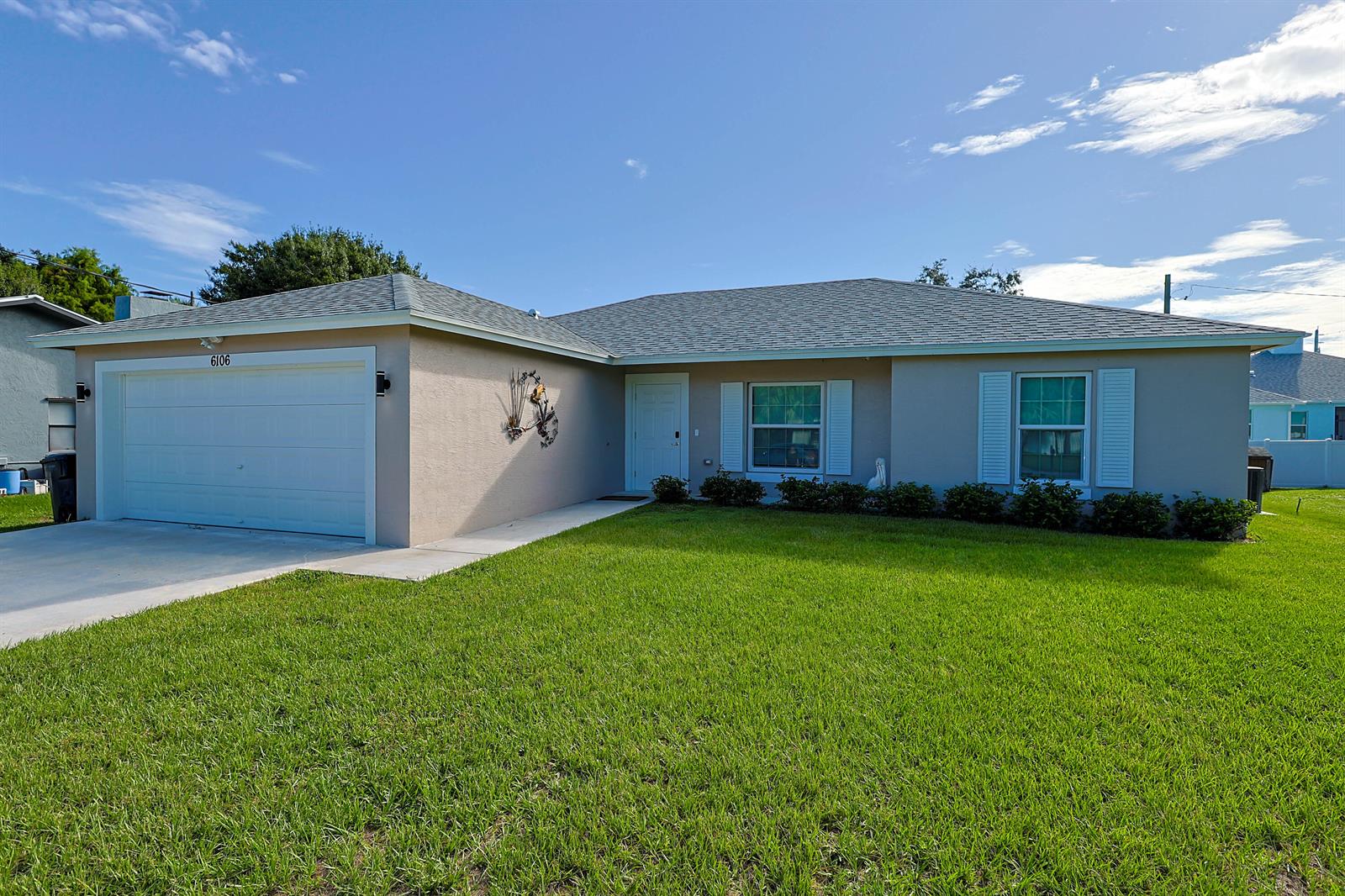 A single-story house with a beige exterior, a two-car garage, and a green lawn — 6106 Bamboo Drive, Fort Pierce FL 34982, FORT PIERCE, FL