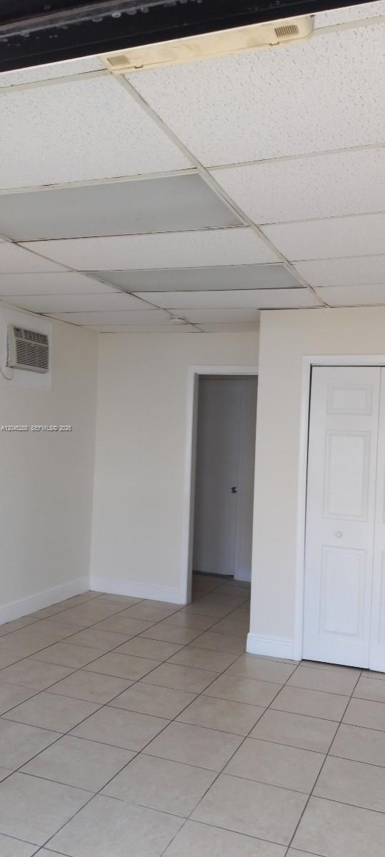 A room with beige walls, a tiled floor, a drop ceiling, and a closet door — 2067 W 62nd St, Hialeah FL 33016, HIALEAH, FL