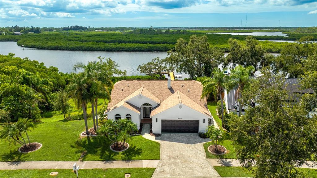 An aerial view shows a single-story house with a paved driveway near a river — 4304 14TH AVENUE E, BRADENTON, FL