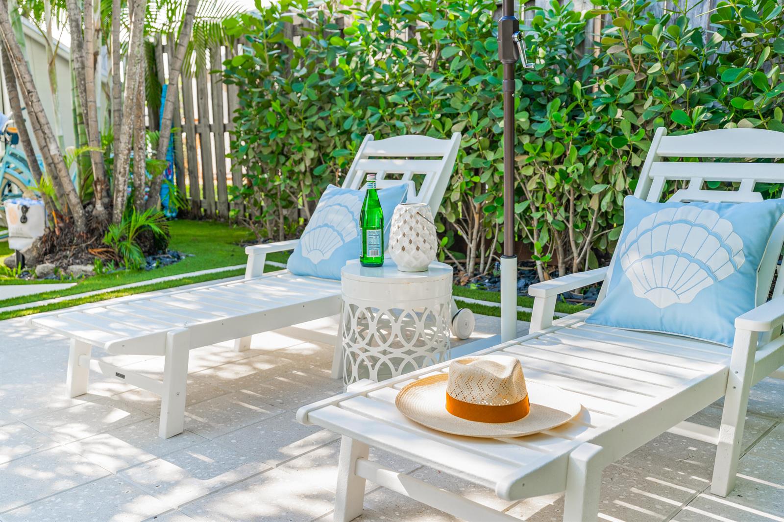 Two white lounge chairs with seashell pillows sit on a patio beside a small table — 7 Fayette Drive, Ocean Ridge FL 33435, OCEAN RIDGE, FL