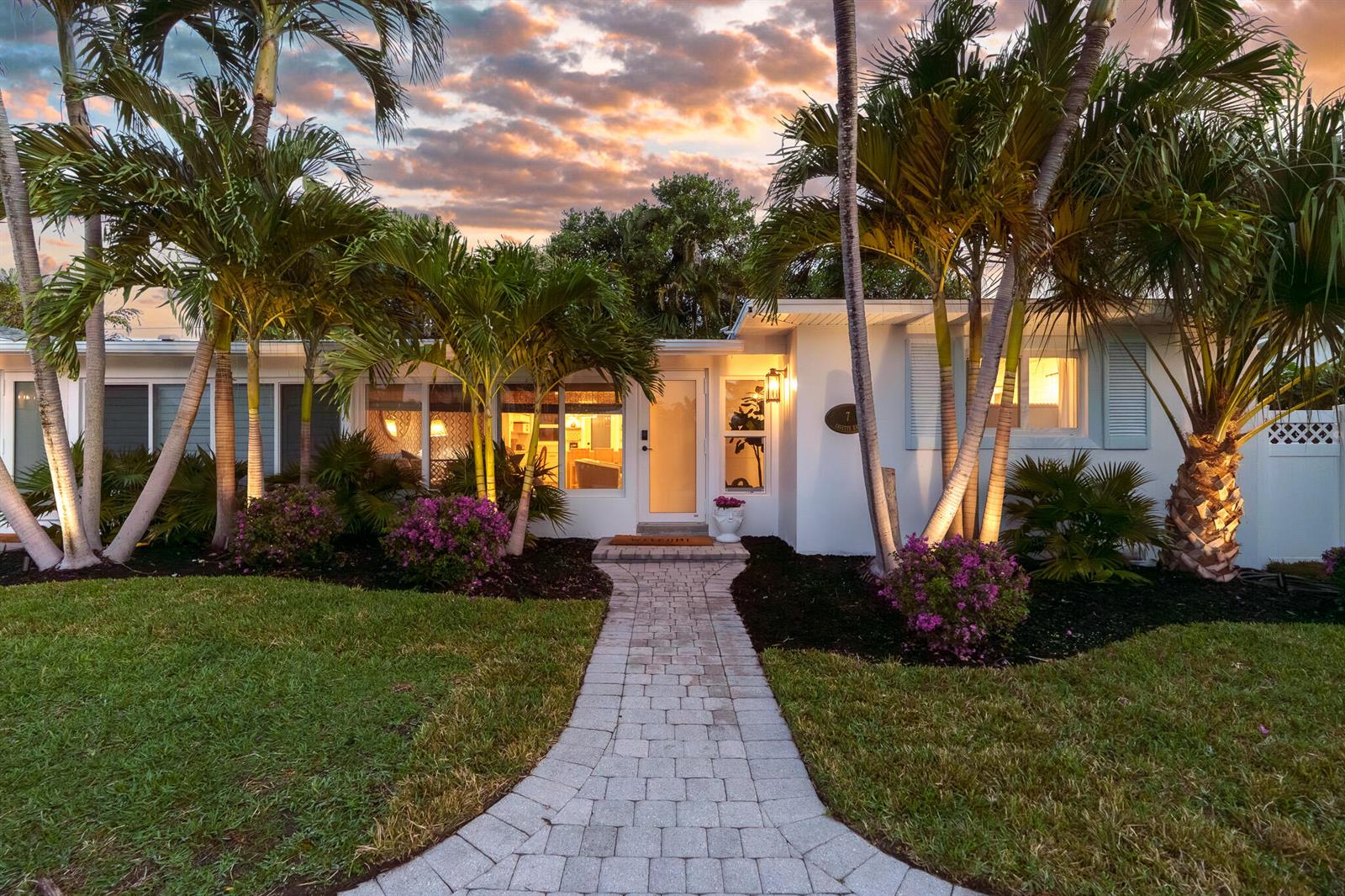 A single-story house with a stone walkway, palm trees, and purple bushes at sunset — 7 Fayette Drive, Ocean Ridge FL 33435, OCEAN RIDGE, FL