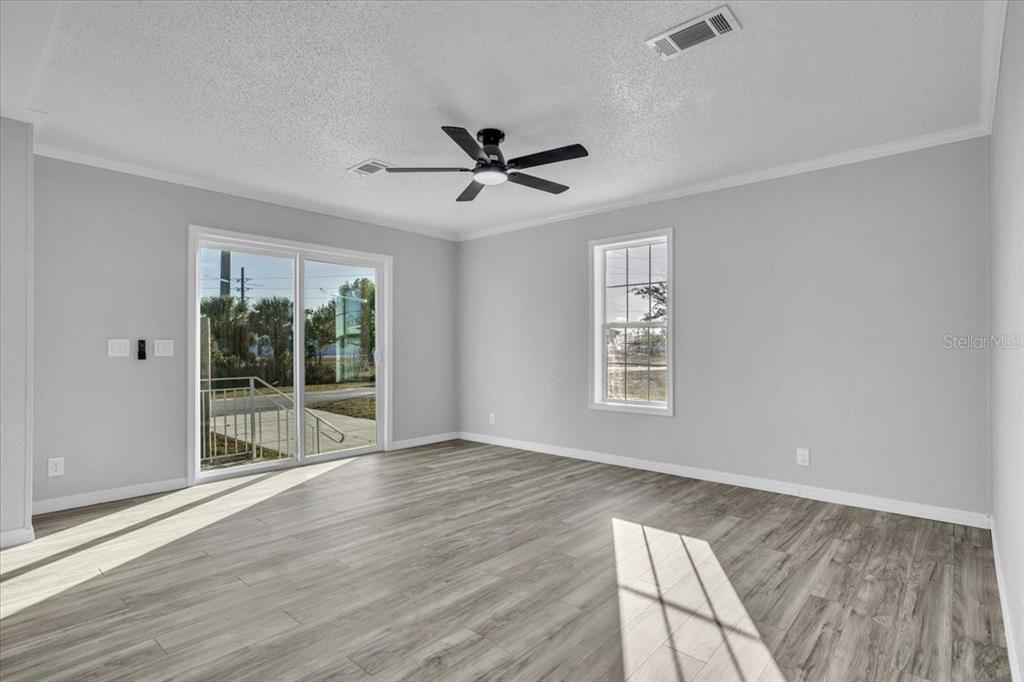 A room with light gray walls, wood-look flooring, a ceiling fan, and sliding glass doors — 2610 CLYDE AVENUE, PUNTA GORDA, FL