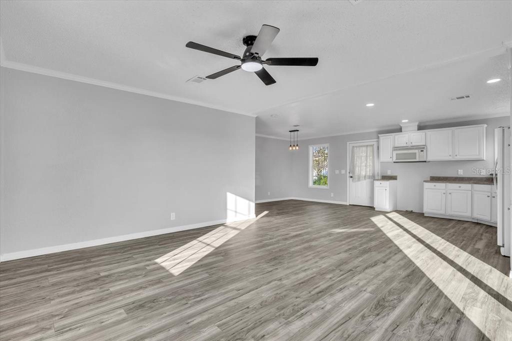 An open-concept living and dining area features light gray walls and wood-look laminate flooring — 2610 CLYDE AVENUE, PUNTA GORDA, FL