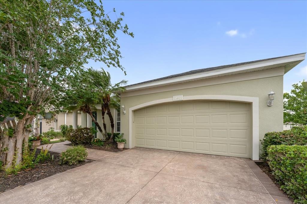 A light green house exterior features a two-car garage and a paved driveway — 11409 56TH STREET CIRCLE E, PARRISH, FL